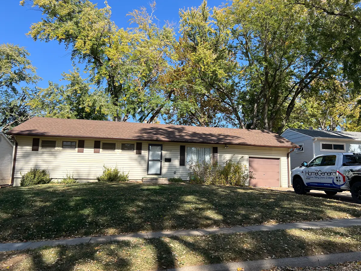 Original exterior of a single-story home before renovations, showing aged siding and an unkept yard with overgrown grass