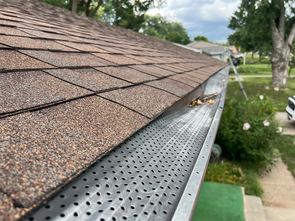 Close-up of an old, damaged gutter filled with debris on the roof of a house