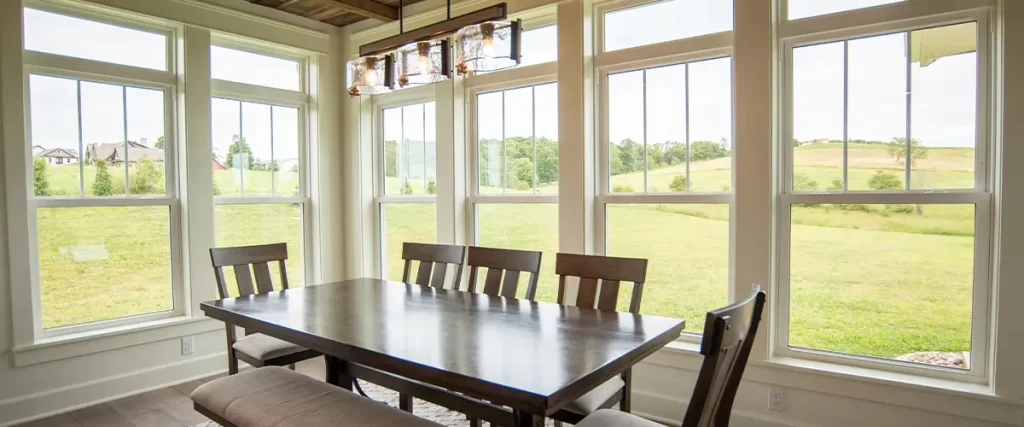 A rustic dining space featuring a wooden ceiling, large double-hung windows, and scenic countryside views.