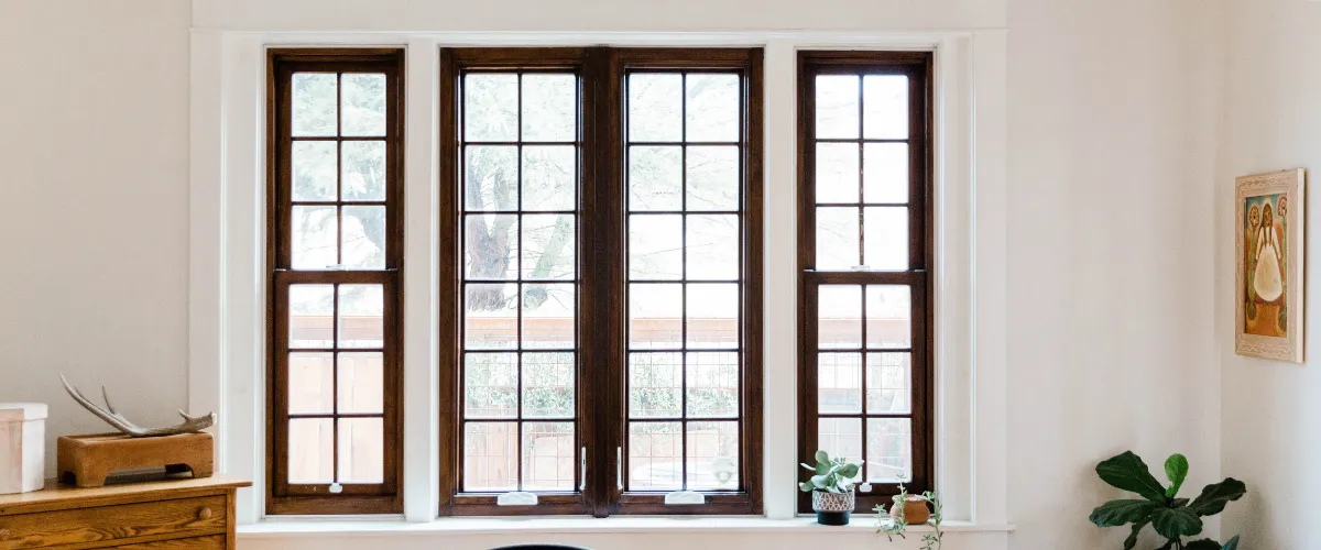 Beautiful traditional wooden-framed windows with a cozy interior and potted plants on the sill.