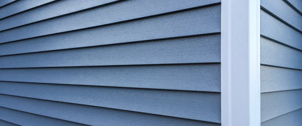 A close-up view of blue-gray horizontal vinyl siding planks on an exterior wall