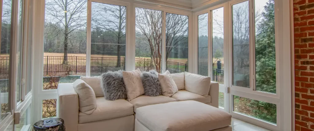 Sunroom with a plush white sofa and large windows overlooking a backyard