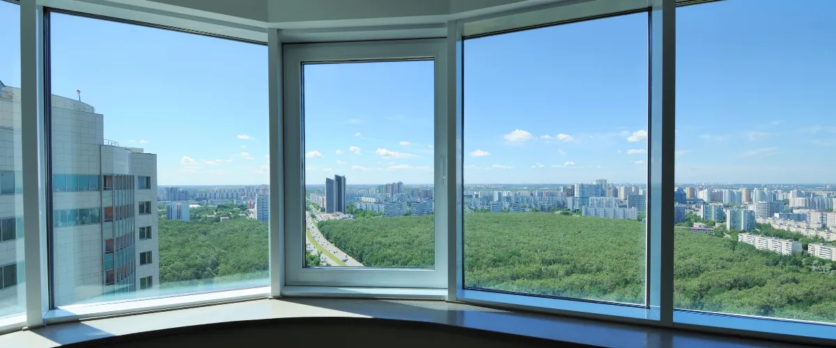 Floor-to-ceiling panoramic windows with a stunning city skyline and green park view.