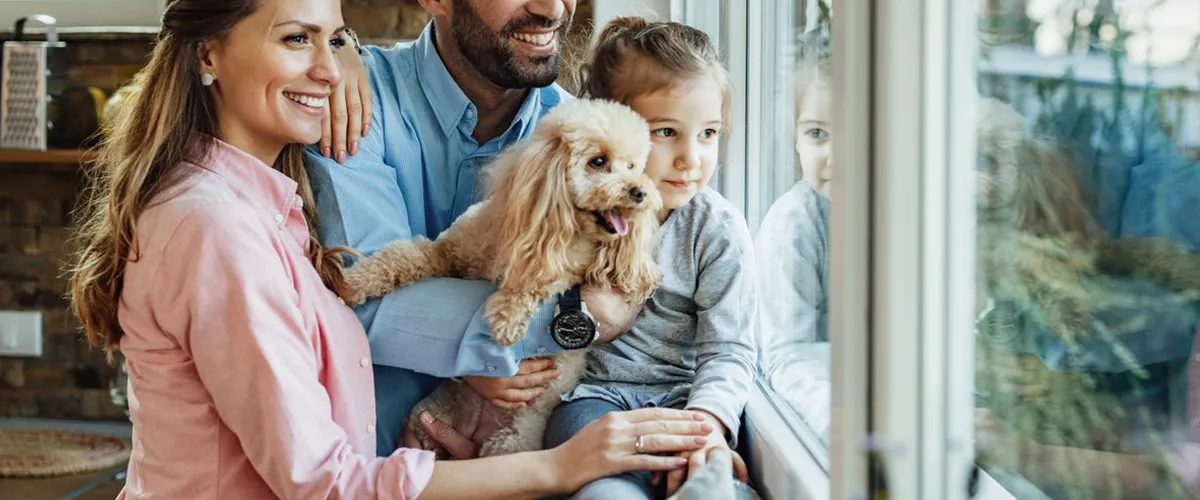 Happy family with child and dog enjoying natural light through new windows in Council Bluffs, IA