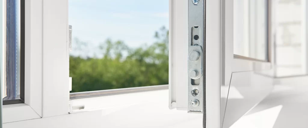 Close-up of modern window lock hardware with open frame and outdoor view