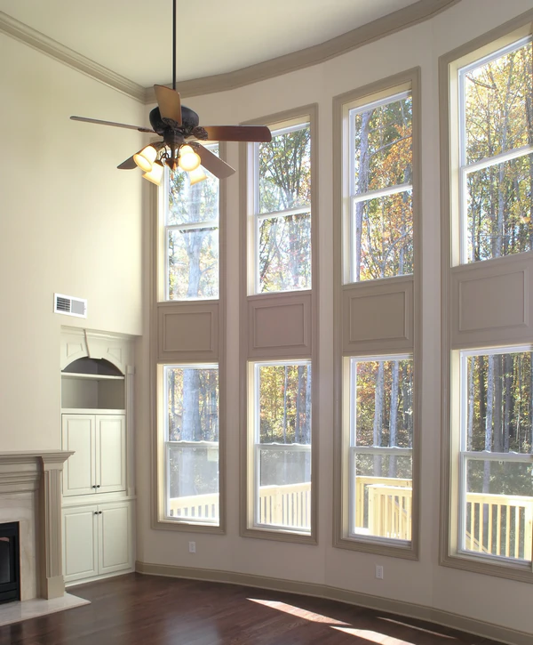 Professional window replacement contractors in Bellevue, NE, showing tall vertical living room windows with a ceiling fan.