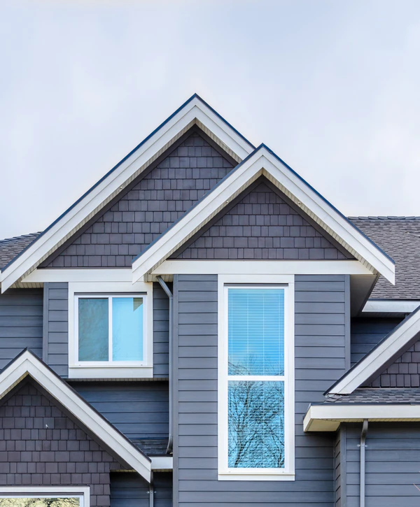 Close-up of a modern home exterior in Lincoln, NE, showcasing professional window installation with crisp white frames against dark gray siding and cedar-style shingles.