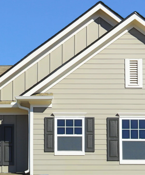 Close-up of a house exterior featuring light beige horizontal and vertical siding installed by siding contractors in Council Bluffs, IA, complete with dark window shutters and white trim against a blue sky.